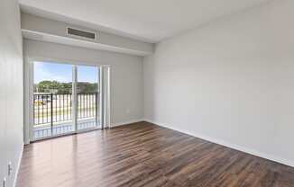 an empty living room with wood flooring and a balcony