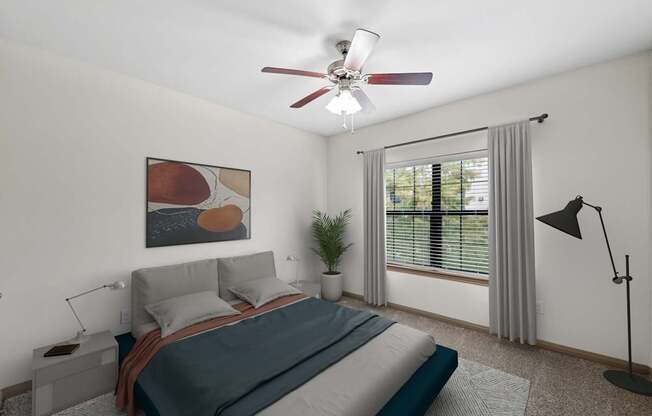 A bedroom with a bed, a ceiling fan, and a window with a plant.