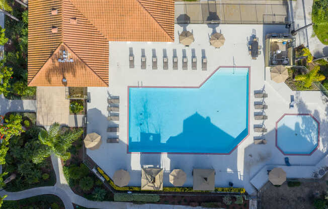 An aerial view of a swimming pool surrounded by lounge chairs and umbrellas.
