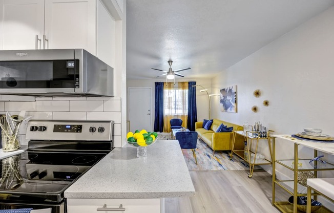 a kitchen and living room with a yellow couch and blue chairs