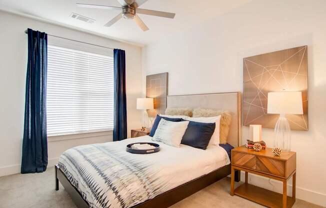 A bedroom with a bed, nightstand, and a ceiling fan.