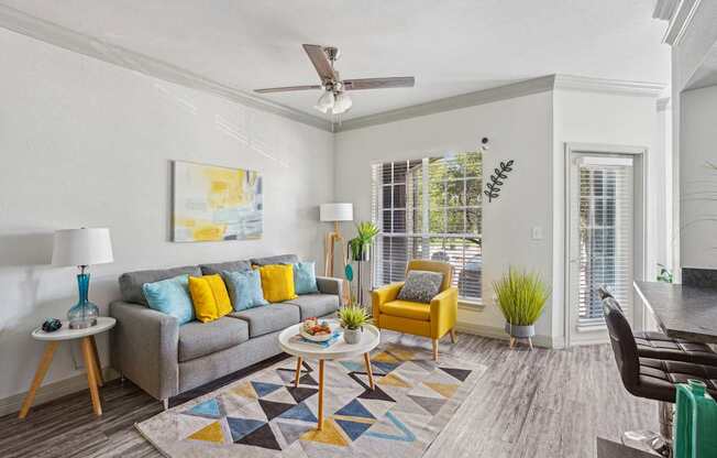 A living room with a grey couch, yellow chair, and a painting on the wall.