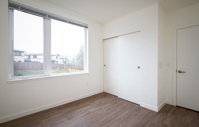 an empty bedroom with a large window and a door