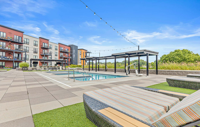 A pool area with a striped sun lounger and a building in the background.