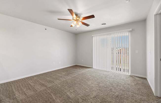 A room with a ceiling fan and carpeted floor.