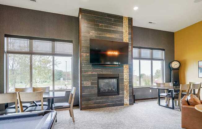 A modern TV lounge with a tiled fireplace, mounted TV, and several seating options.