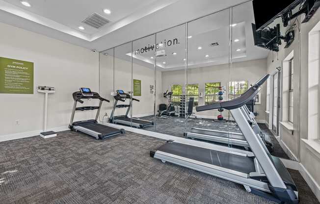 a gym with treadmills and other exercise equipment in a glass walled room