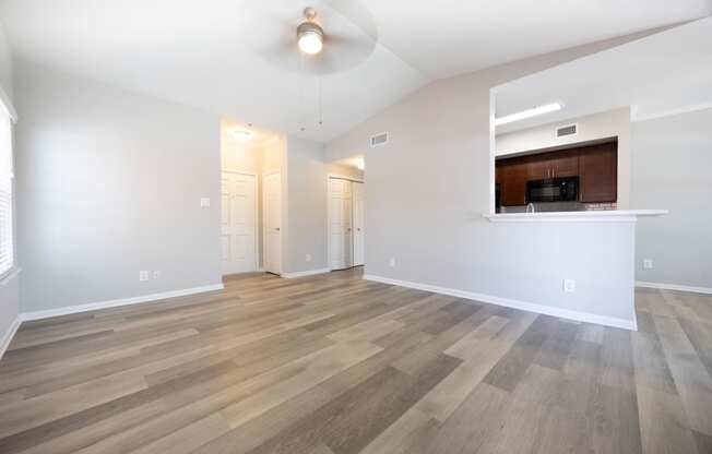 the living room and kitchen of an empty apartment with wood flooring