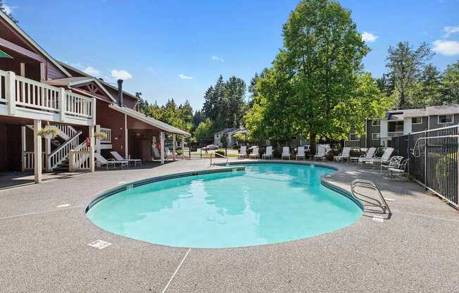 A large outdoor swimming pool surrounded by a fence and trees.