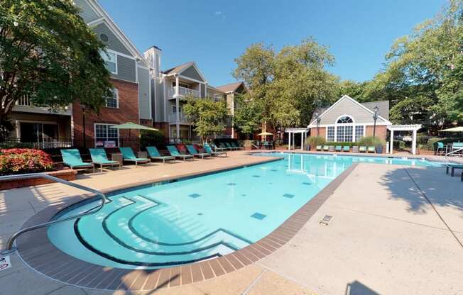 a swimming pool with lounge chairs and umbrellas in front of a brick building at Autumn Park Apartments, North Carolina