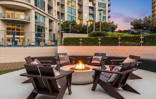 A fire pit sits in the middle of a patio surrounded by chairs.
