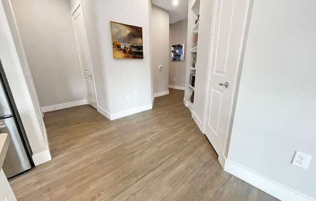 a living room and hallway with wood flooring and white walls