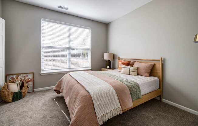 A bedroom with a bed, pillows, and a basket on the floor.