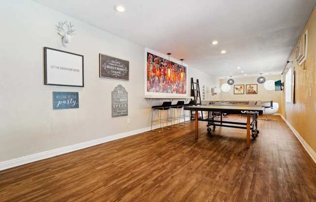 a game room with a ping pong table and paintings on the wall