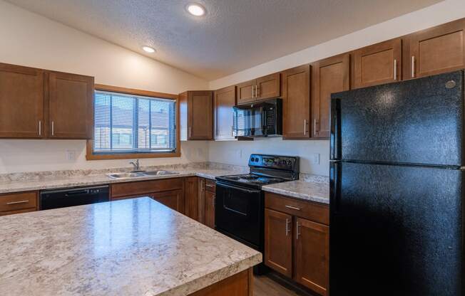 a kitchen with black appliances and white countertops. Fargo, ND Westwood Apartments
