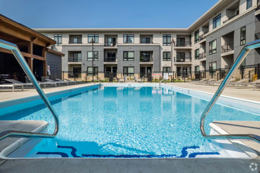 a swimming pool with an apartment building in the background at Two Points Crossing, Verona, WI