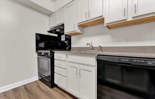 a kitchen with white cabinets and black appliances