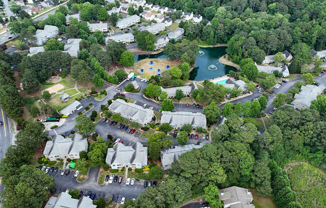 A bird's eye view of a residential area with houses, roads, and a lake.