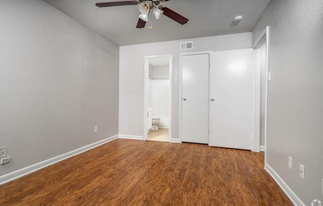 an empty living room with wood flooring and a ceiling fan