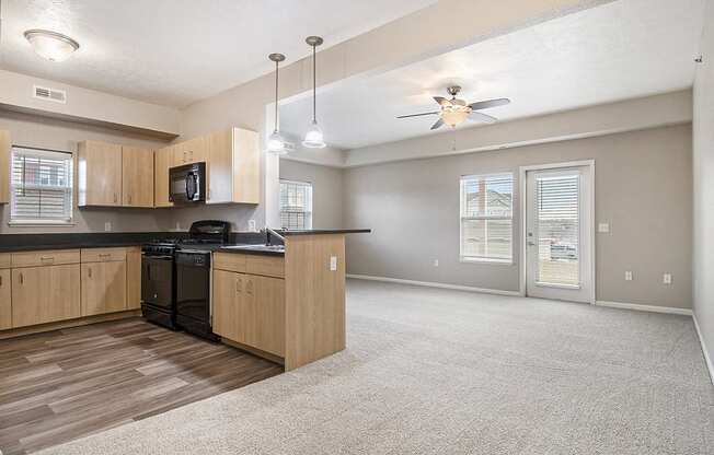 A kitchen with wooden cabinets and an enlarged living room at Lynbrook Apartments and Townhomes, Elkhorn, NE, 68022