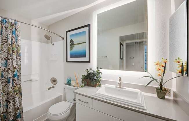 a bathroom with a white toilet next to a white bathtub and a white sink with a  at Laguna Gardens Apts., Laguna Niguel, CA