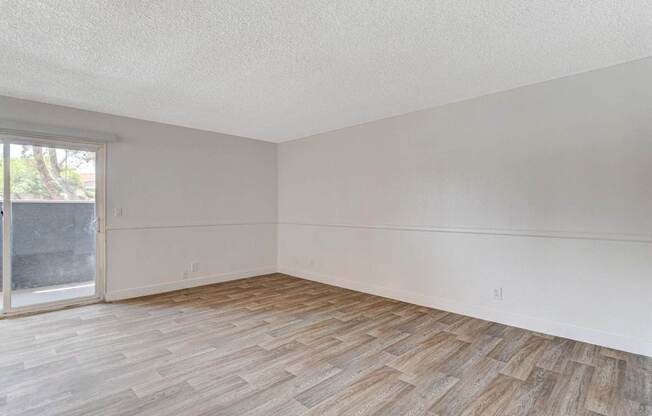 A room with wooden flooring and a sliding glass door.