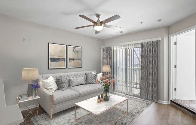 A living room with a grey couch, a white coffee table, and a ceiling fan.