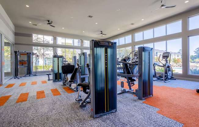 A gym with orange carpet and treadmills.