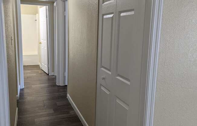 a hallway with white doors and a wood flooring in a home