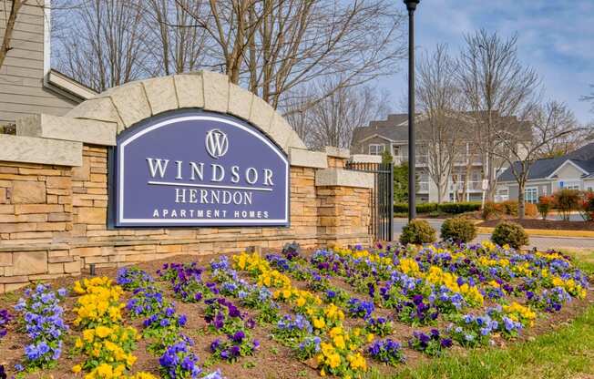 a sign that says windsor herndon apartments with flowers in front of it
