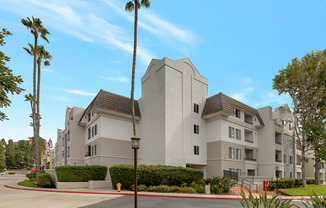 a large white apartment building with palm trees in front of it