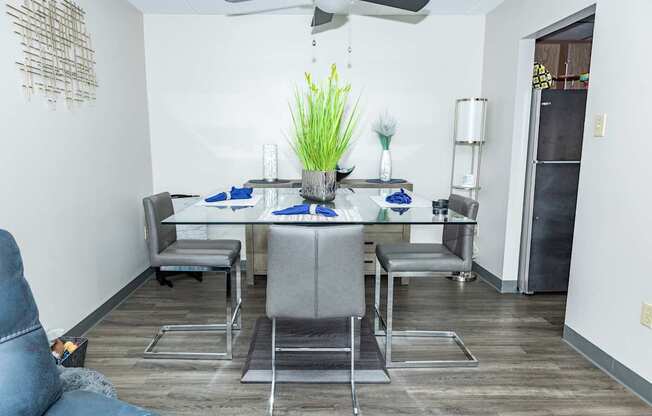 A dining room with a table set for two and a blue couch.