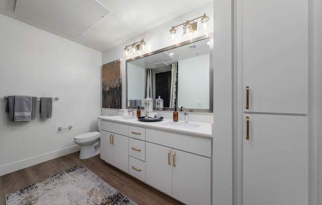 A bathroom with a white toilet, sink, and cabinets.