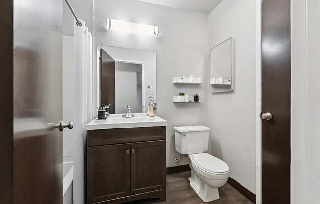 Model Bathroom with Dark Wood Cabinets and Wood-Style Flooring at Creek at 2645 Apartments located in Sacramento, CA.