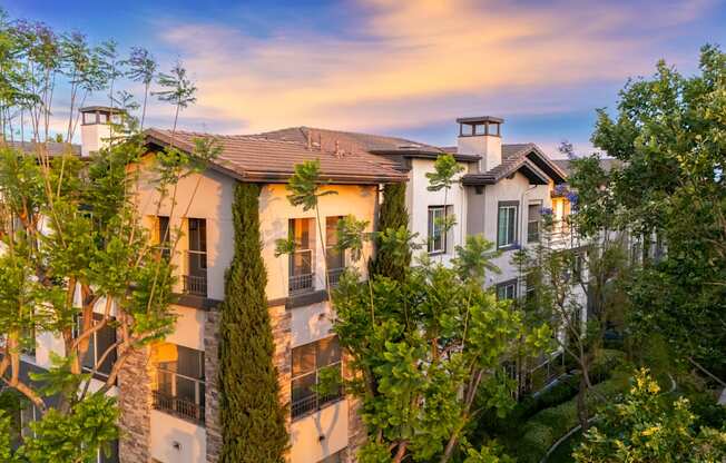 A large house with a balcony is surrounded by trees.