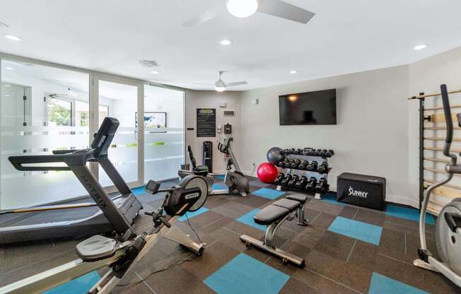 a gym with exercise equipment and a television