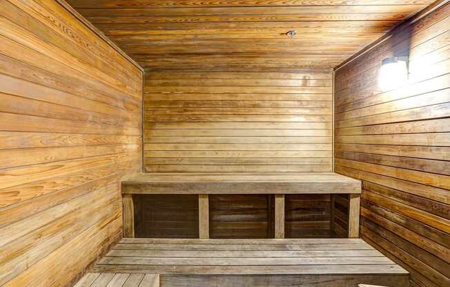 A wooden sauna with a bench and a light on the wall.