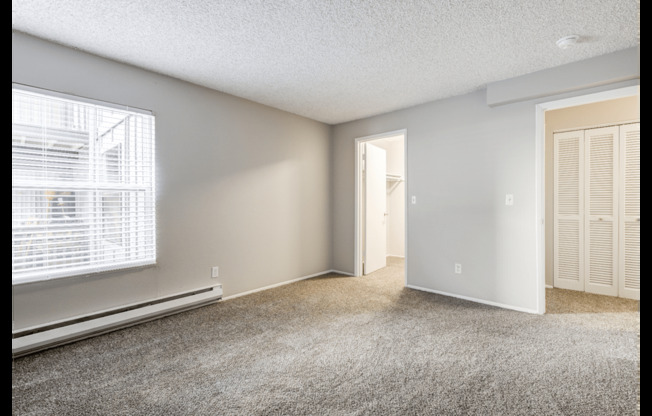 A room with a window, a door, and a wall-mounted air conditioner unit.