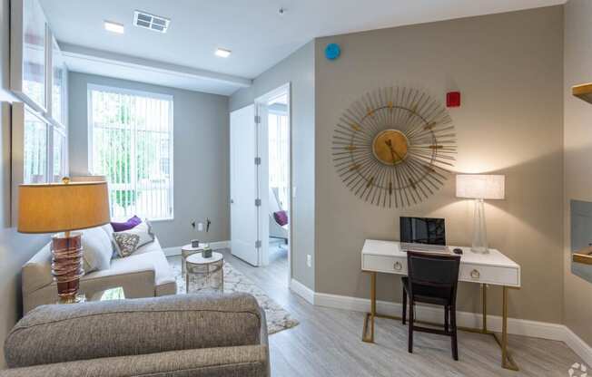 a living room with a desk and a mirror on the wall