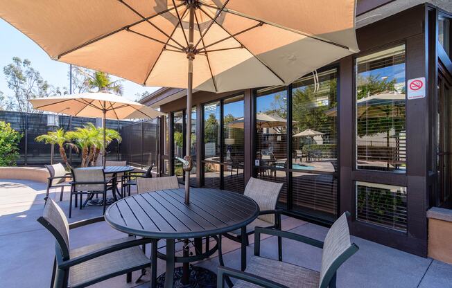 A patio with a table and chairs under an umbrella.