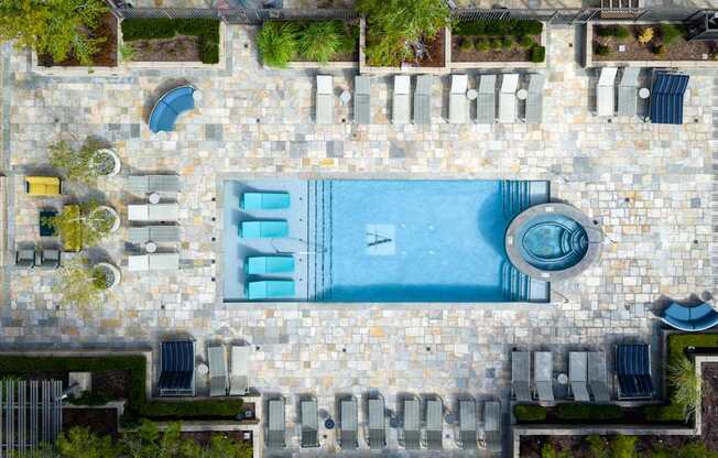 A pool surrounded by stone and patio furniture.