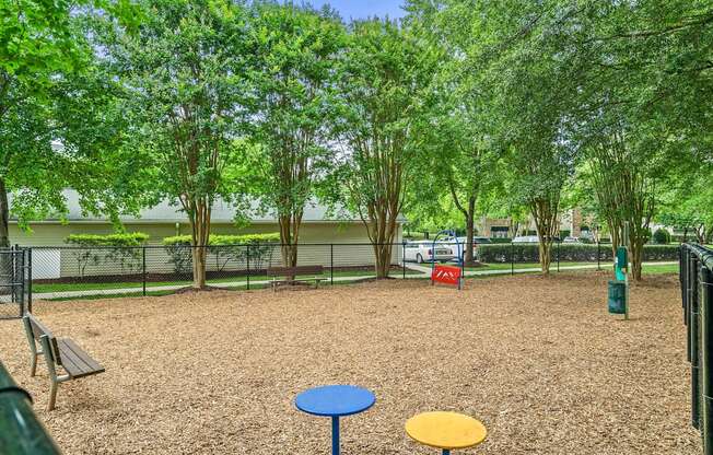 A playground with a blue and yellow table in the middle of a brown gravel area.
