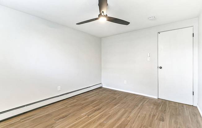 Bright and airy room with sleek wood floors and a modern ceiling fan, perfect for a cozy bedroom retreat.