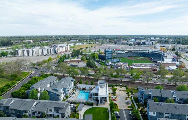 A large stadium is surrounded by apartment buildings and a parking lot.
