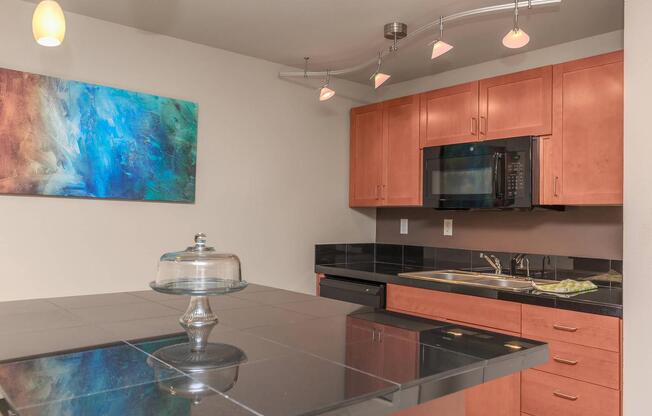 a kitchen with a black counter top and a glass cake stand on top of it