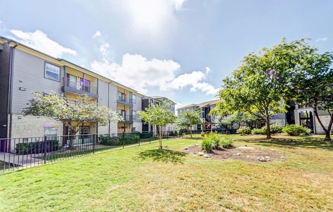 Fenced in dog park with large green space and shade trees