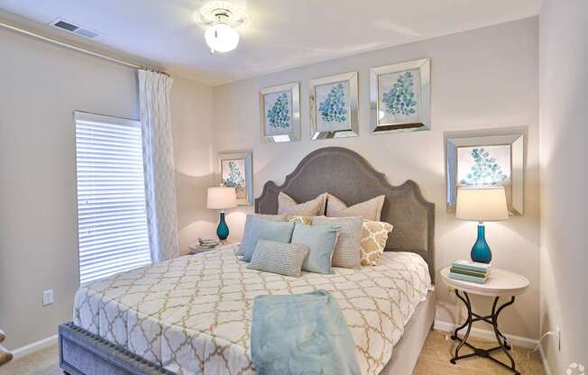 A bedroom with a large bed and a small table with a lamp on it.