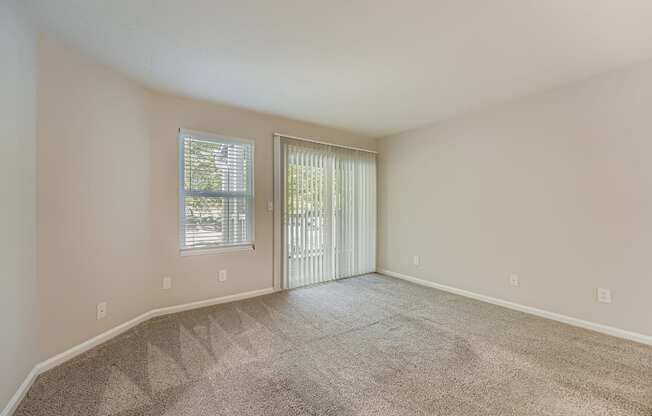 A room with a carpeted floor and a sliding glass door.