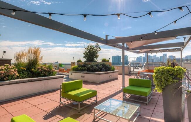 a roof top patio with green chairs and a view of the city