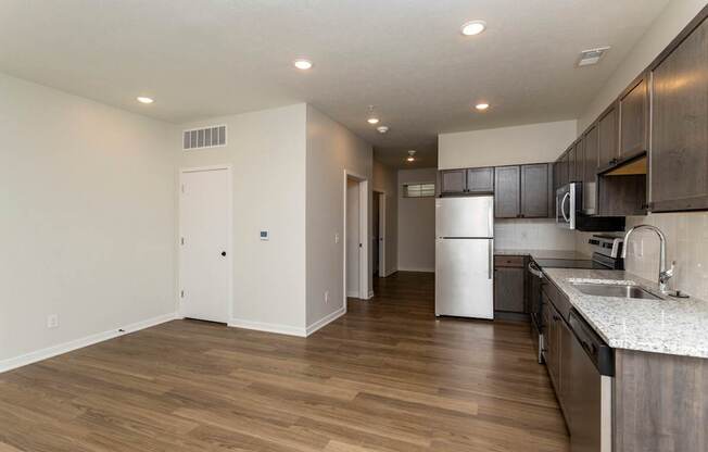 A kitchen with a white refrigerator and wooden floors.